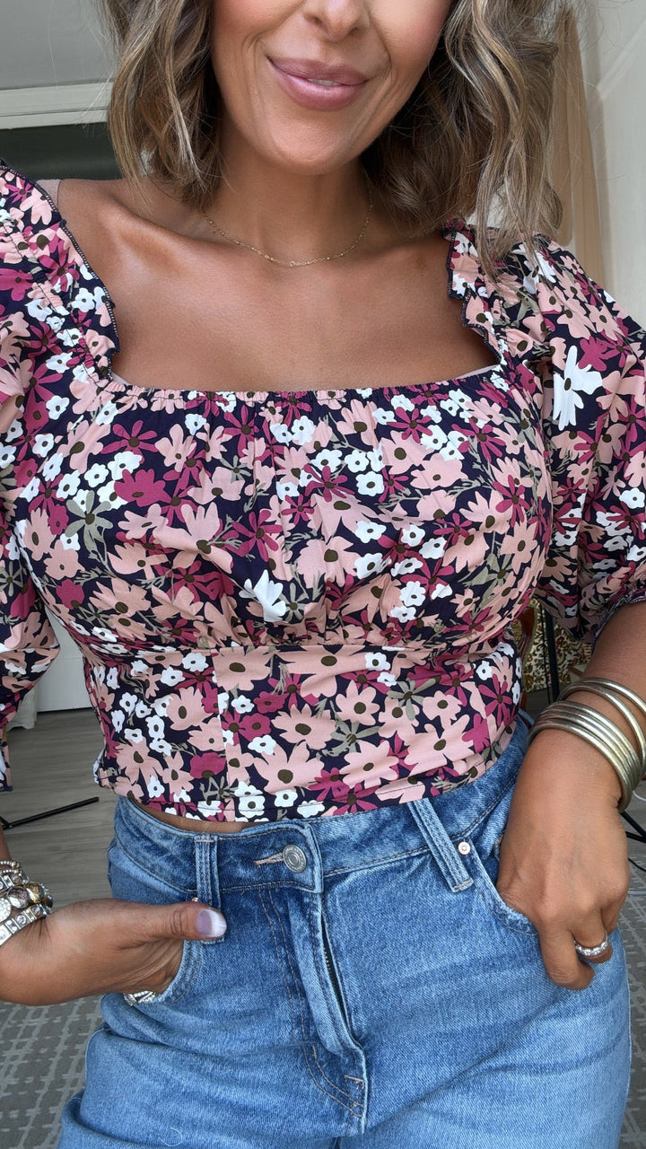 Woman wearing a floral top and blue jeans with a blurred background